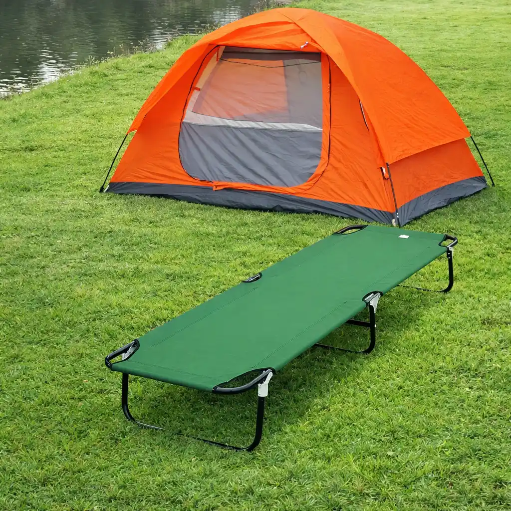 Outdoor camping setup with an orange tent and portable camping cot on grassy ground
