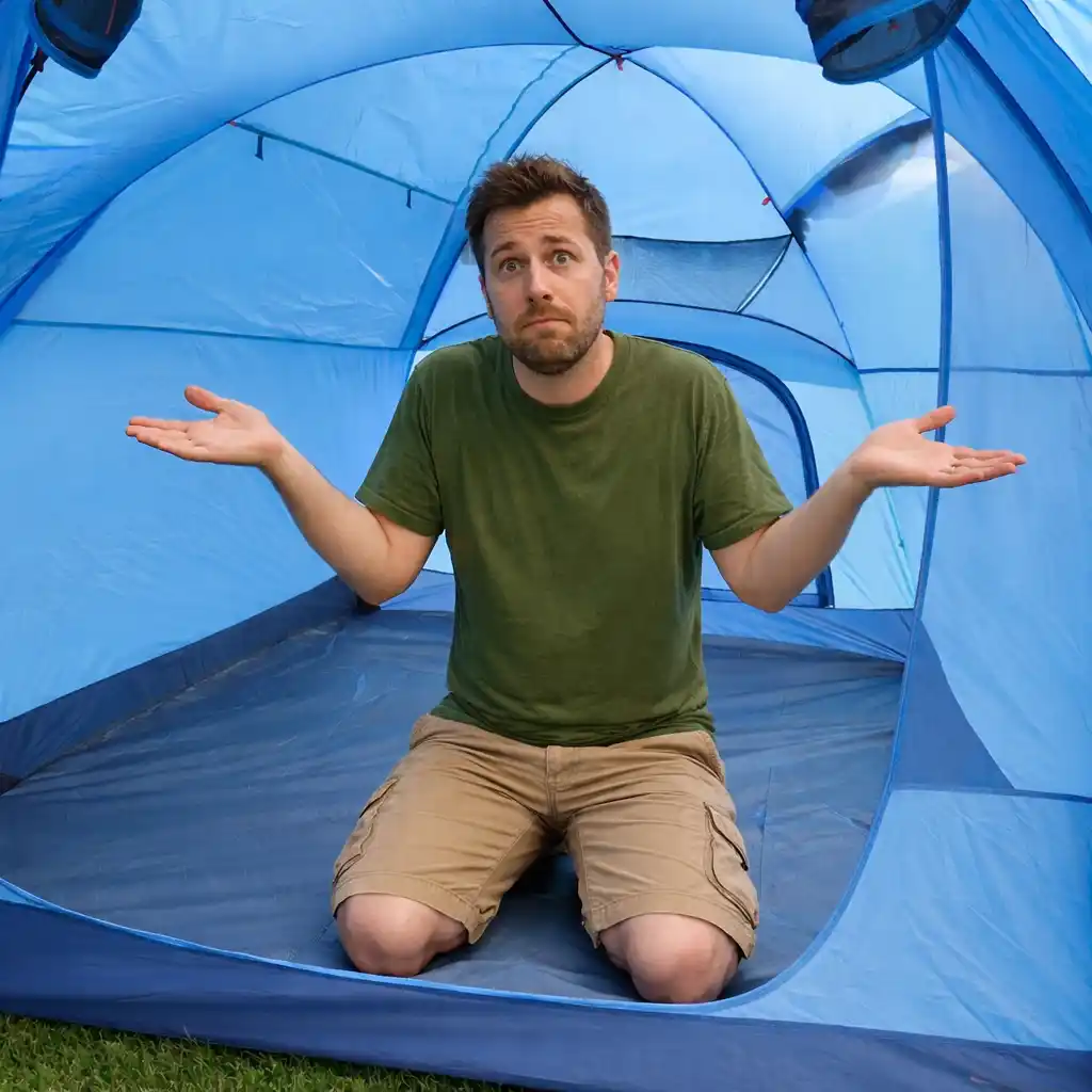 Man kneeling inside a light blue camping tent with arms outstretched, looking confused.