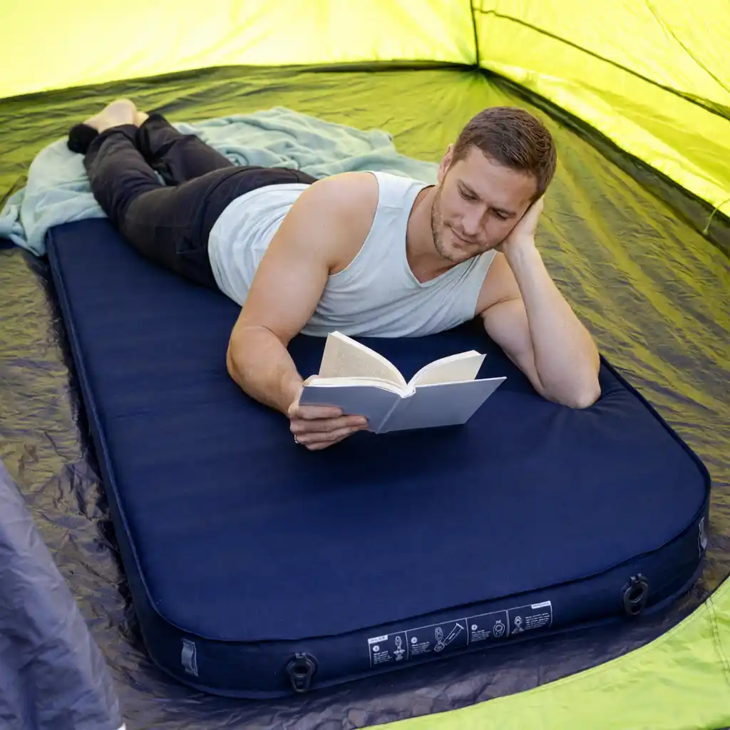 man relaxing on an inflatable sleeping pad inside a camping tent