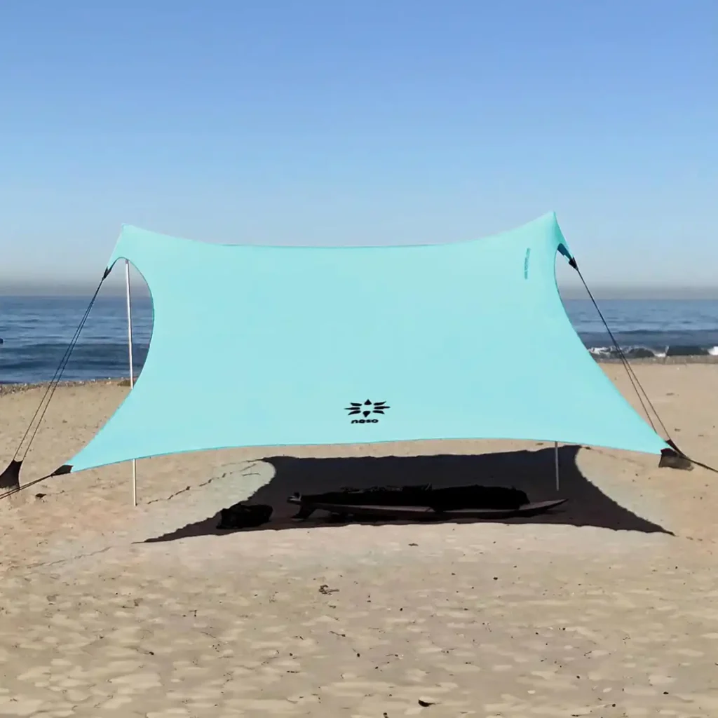Neso Gigante beach canopy anchored in sand with flexible fabric providing shade by the ocean
