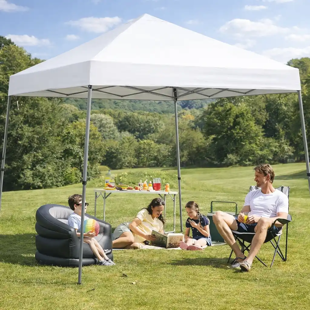 white pop-up canopy set up at campsite with family relaxing underneath in a grassy outdoor setting