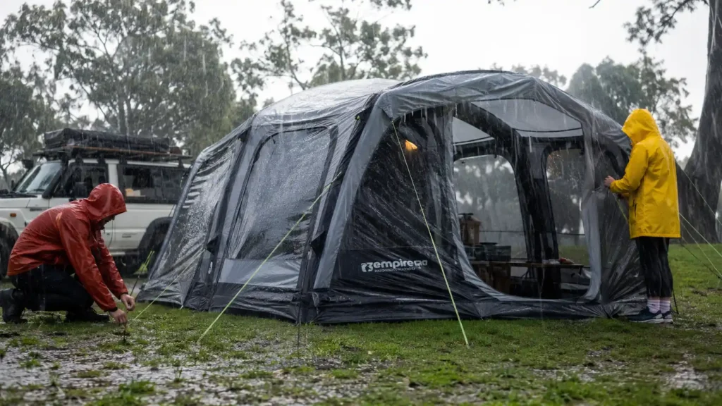 Best inflatable camping tents for heavy rain with campers wearing colorful rain jackets during a rainy camping trip
